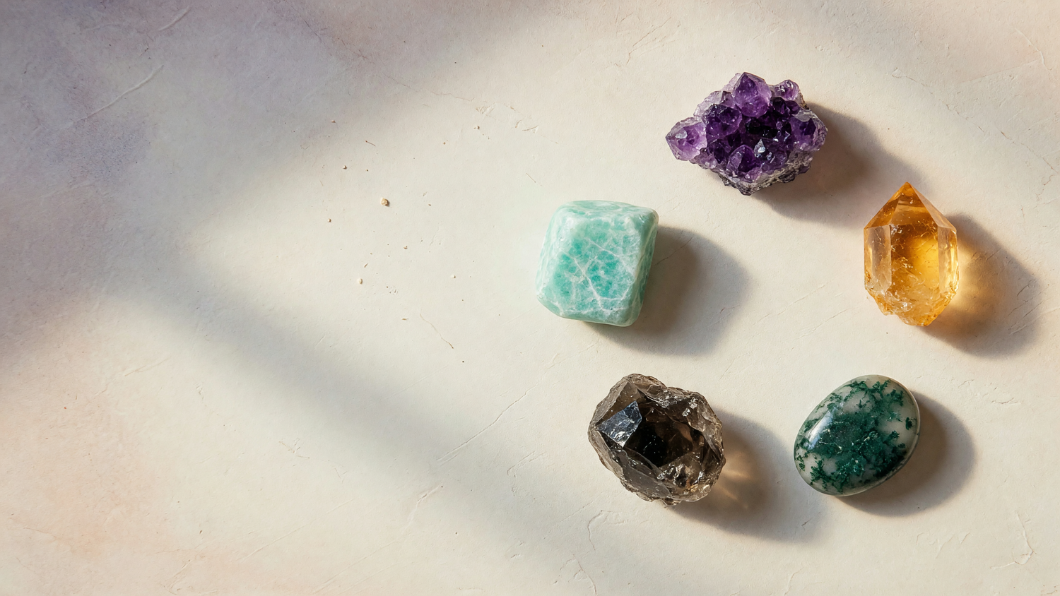 Kairo banner 5 Element Compass desktop - five raw crystals arranged in a ring on cream plaster